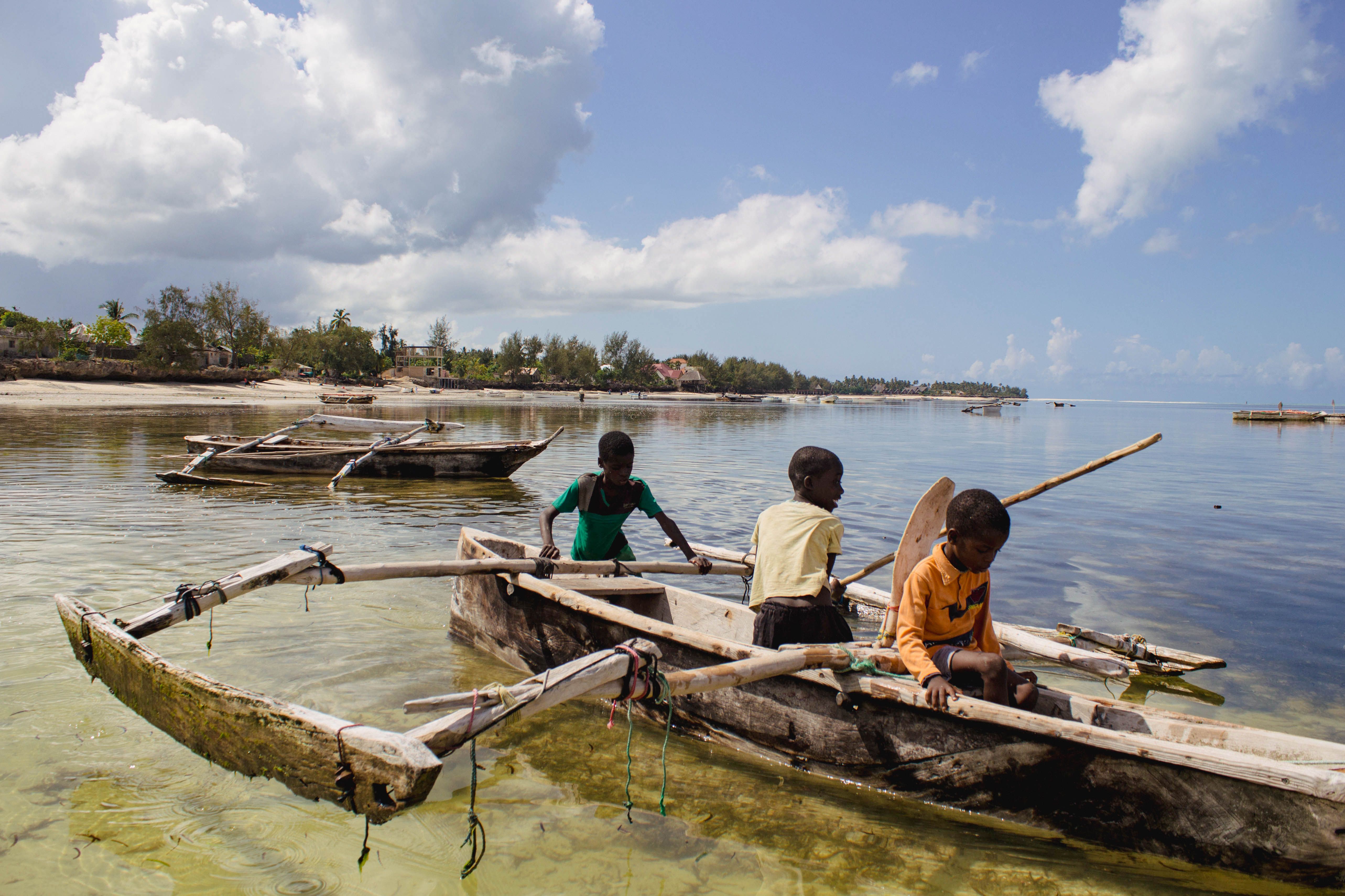 Local children with traditional outrigger boats on the Zanzibar coast